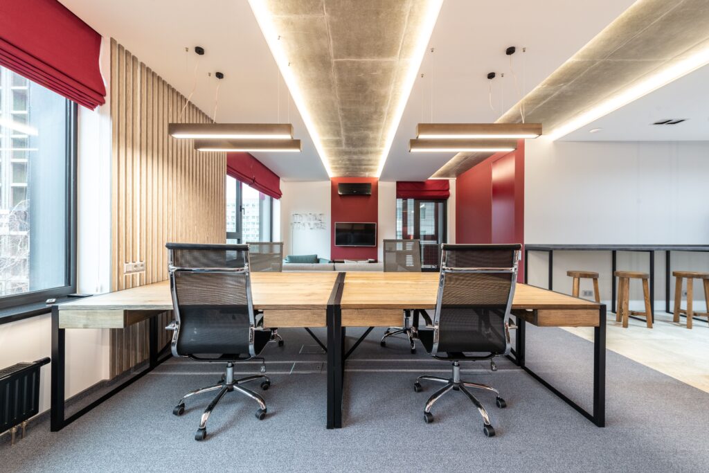 Interior de um local de trabalho moderno com mesa e cadeiras de madeira perto da janela com persiana sob as luminárias, Luz direta e Iluminação para Home Office.