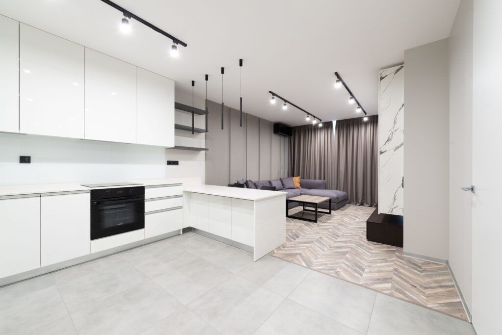 Sleek open-plan kitchen and living area with contemporary design featuring white cabinets and neutral tones.