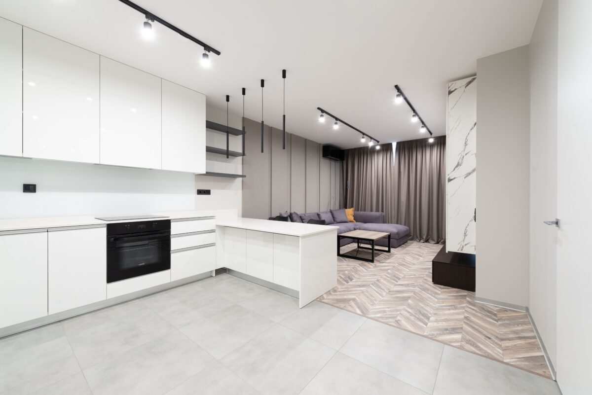 Sleek open-plan kitchen and living area with contemporary design featuring white cabinets and neutral tones.
