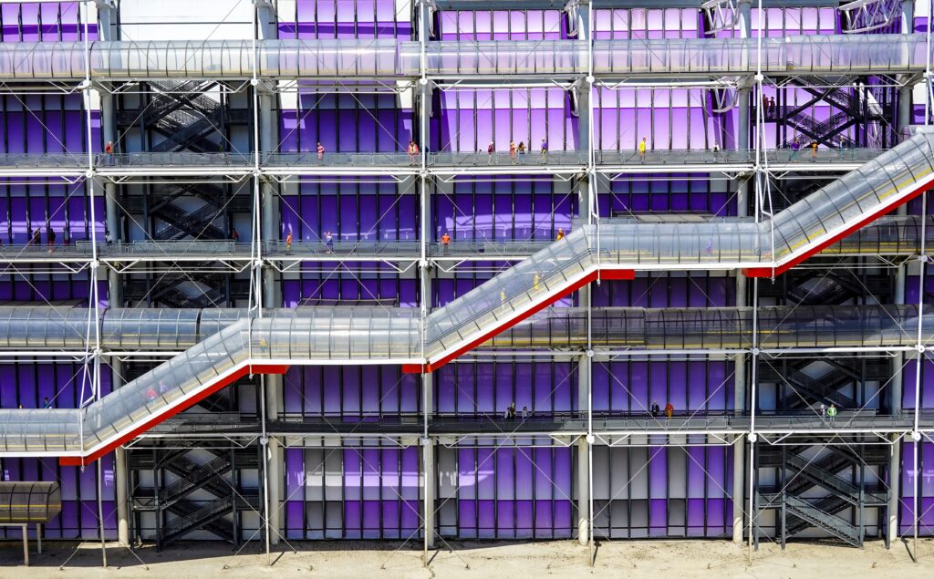 Exterior marcante de um edifício moderno apresentando painéis roxos ousados e escadas transparentes únicas, demonstrando a psicologia do roxo como um manifesto de singularidade urbana que quebra a monotonia da malha cinzenta.