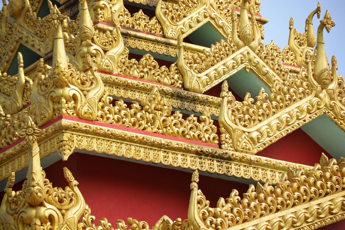 Foto detalhada de decorações douradas ornamentadas em um templo budista, demonstrando a psicologia do ouro através do seu simbolismo de sabedoria divina, perenidade e da irradiação térmica psicológica que acolhe o olhar.