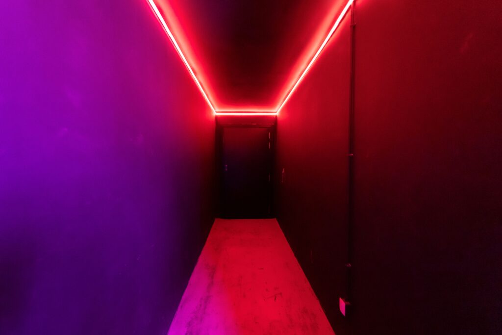Um corredor vibrante iluminado por neon, apresentando uma mistura marcante de luzes vermelhas e roxas que evoca a psicologia do vermelho através do estímulo físico e da profundidade cênica.