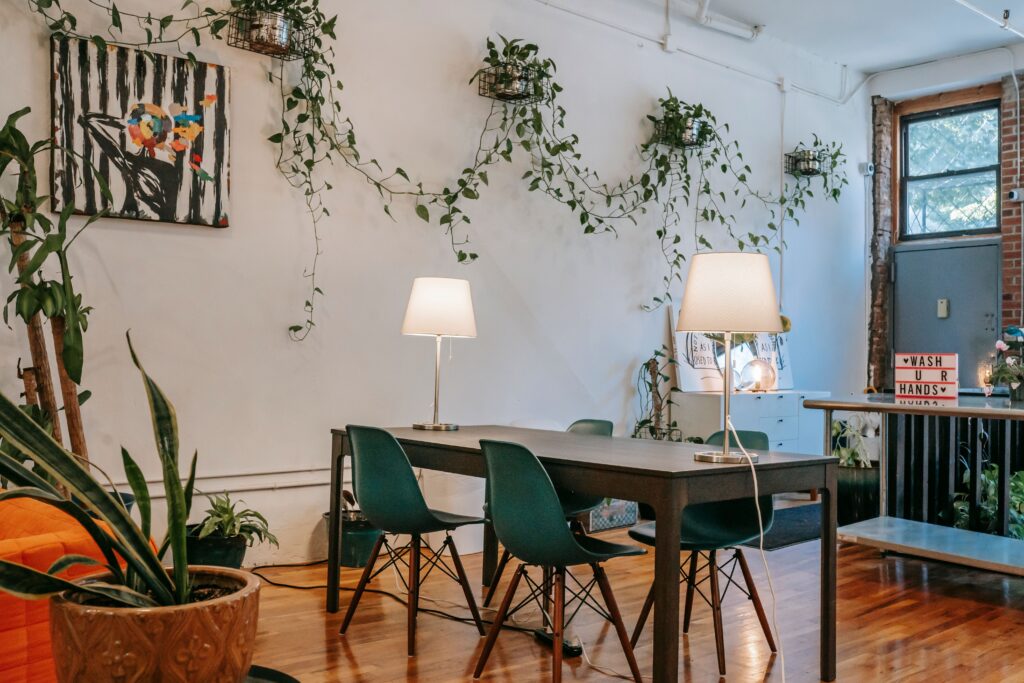 Sala de jantar contemporânea com mobiliário moderno, decorada com plantas em vasos e um quadro em parede branca, localizada em uma casa aconchegante e iluminada. Psicologia do verde