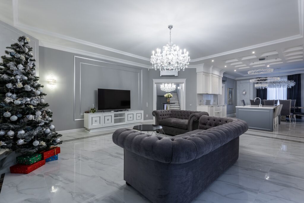 Interior de uma sala de estar contemporânea vazia com mobiliário elegante e uma árvore de Natal festiva durante o dia, onde a psicologia da prata atua através das estruturas metálicas para criar leveza visual e contrastar harmonicamente com os elementos quentes.