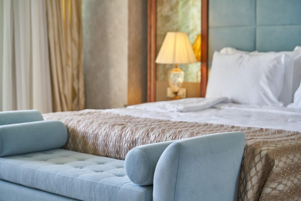 Um luxuoso quarto de hotel com cama confortável, demonstrando o uso de tons azuis relaxantes como cores para o quarto.